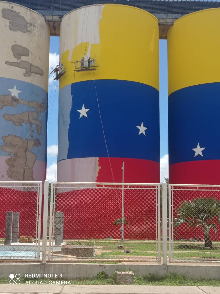 Intervención visual de silos industriales pintados con la bandera de Venezuela — proyecto Pinturas Coloreal gran formato