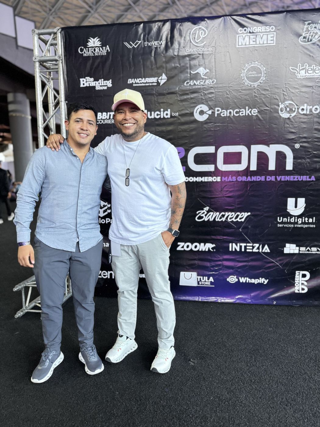 Juan Balza con un asistente frente al backdrop de eCom, el evento de ecommerce más grande de Venezuela