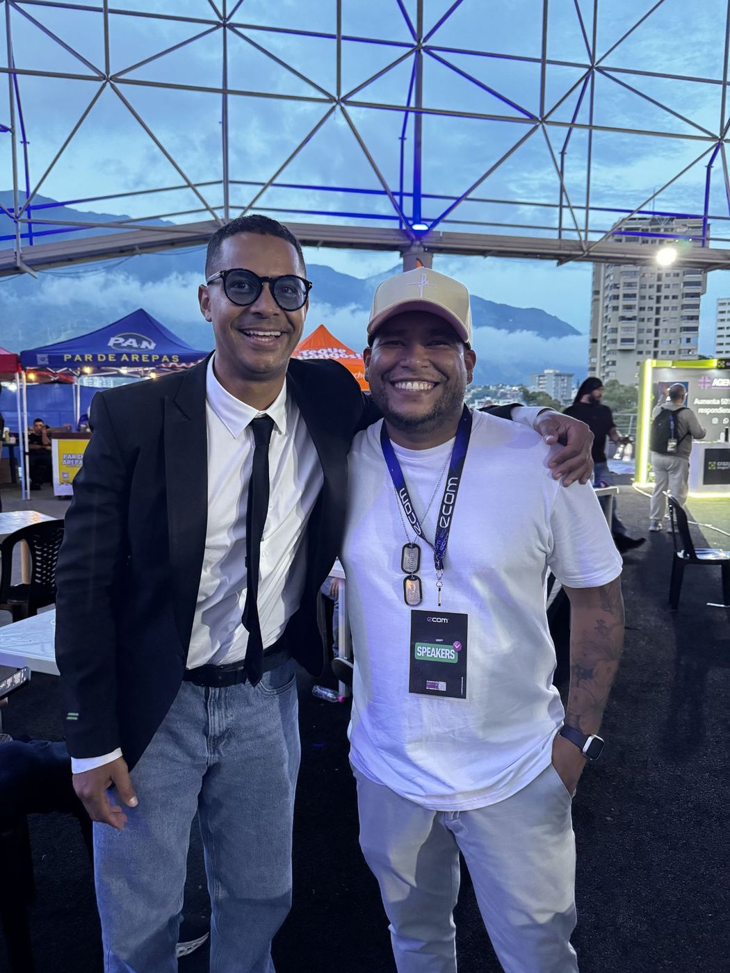 Juan Balza con un colega en la terraza de eCom Venezuela al atardecer, con la montaña de fondo